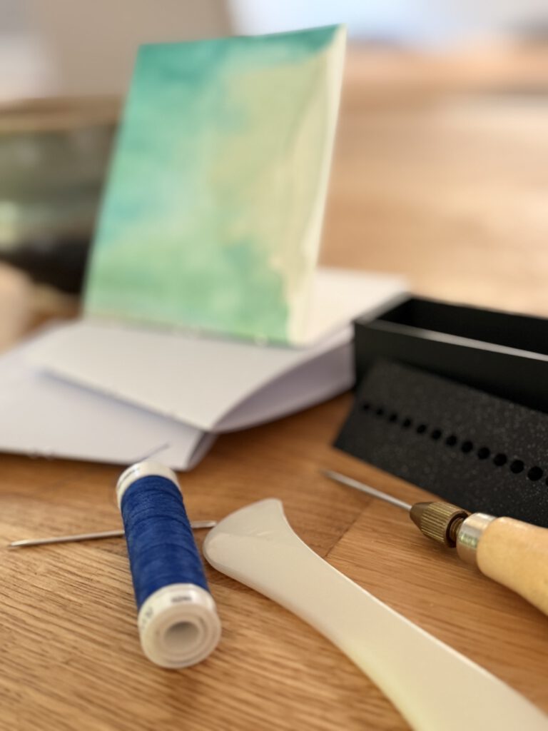 Handgebundenes Heft mit Faden und Werkzeug